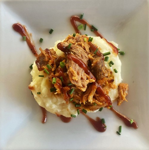 Shredded rib meat over a scoop of mashed potatoes, drizzled with BBQ sauce and sprinkled with green onions